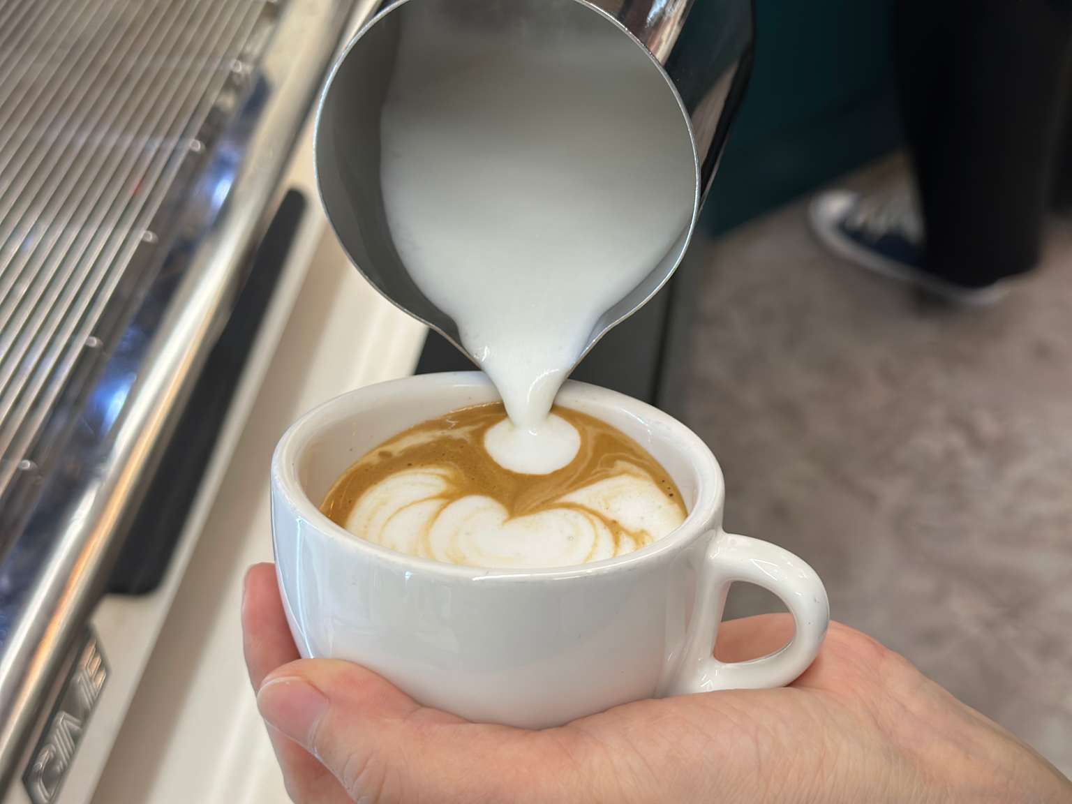 에스프레소에 우유를 부어 라떼 아트를 만드는 바리스타