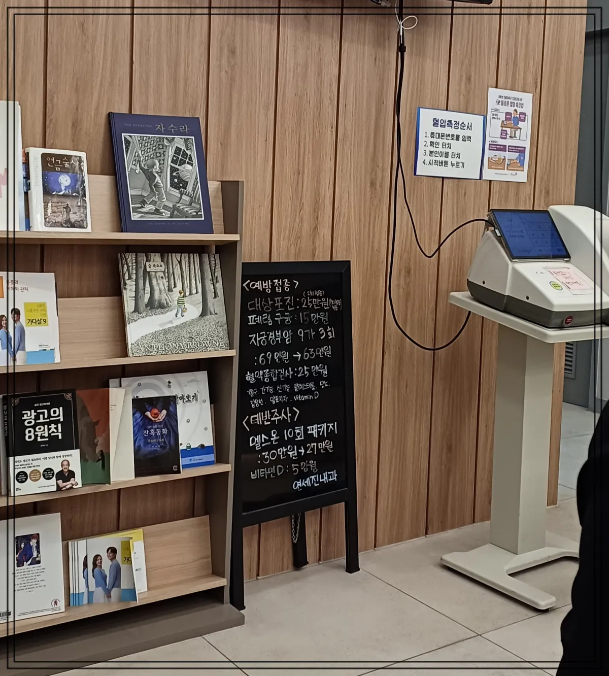 병원-내부-사진-혈압재는-기계와-안내판넬-책장이-있다
