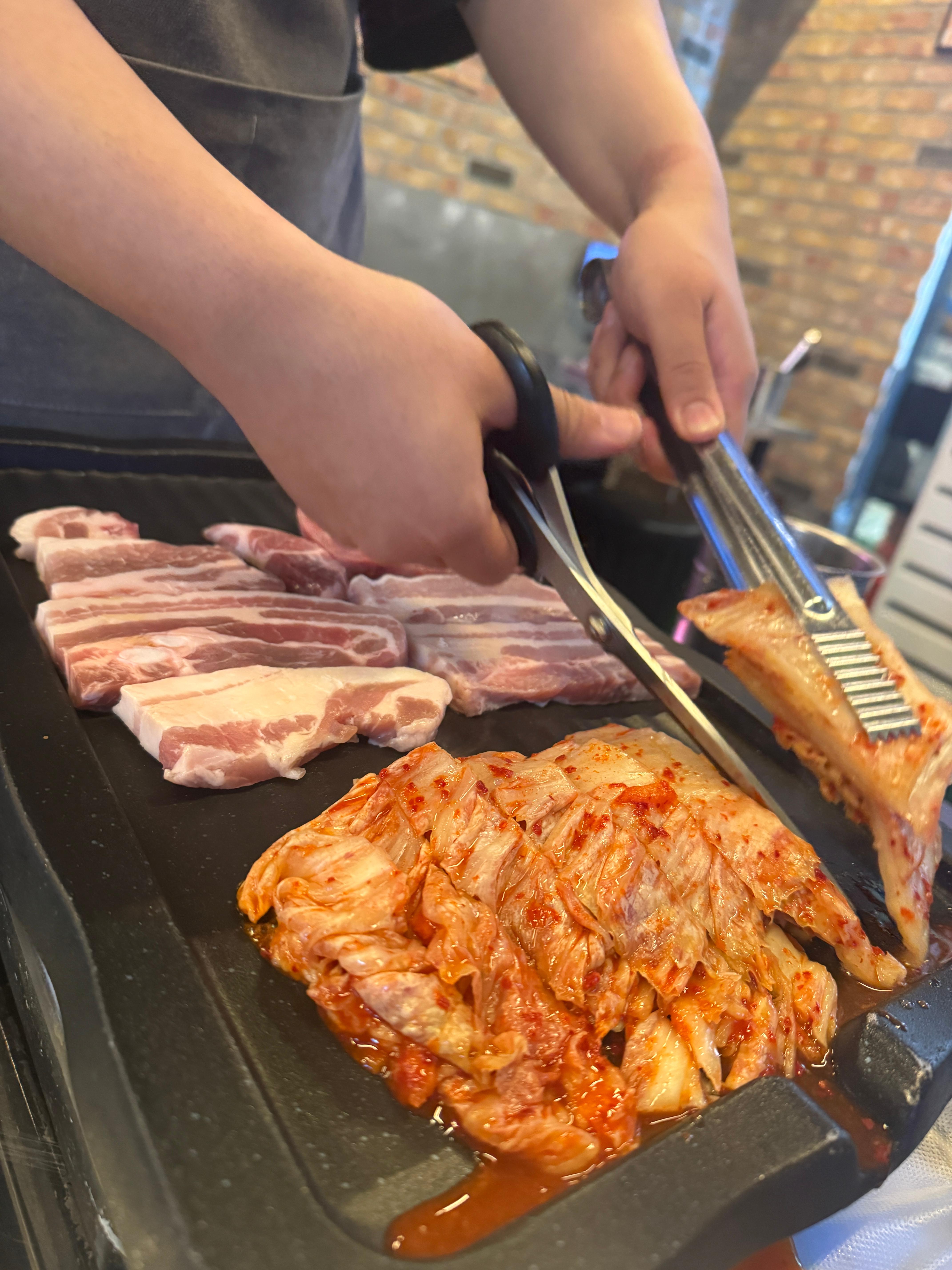 마곡 고기집 신김치 생도야지 마곡본점에서 직원이 직접 삼겹살과 통김치를 불판에 올려 구워주는 모습