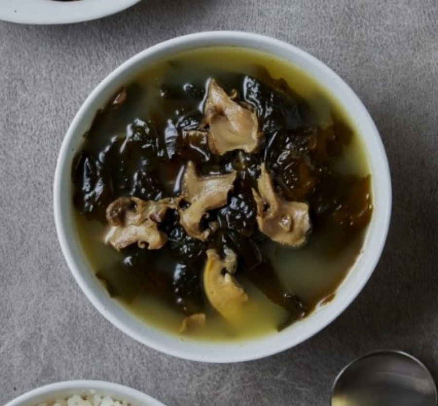 바다에서 채취를 한 미역을 깨끗하게 세척을 한 후에 물을 붓고 끓인 미역국을 동그랗고 하얀 그릇에 가득 담아둔 것을 위에서 확대를 하여 찍은 사진