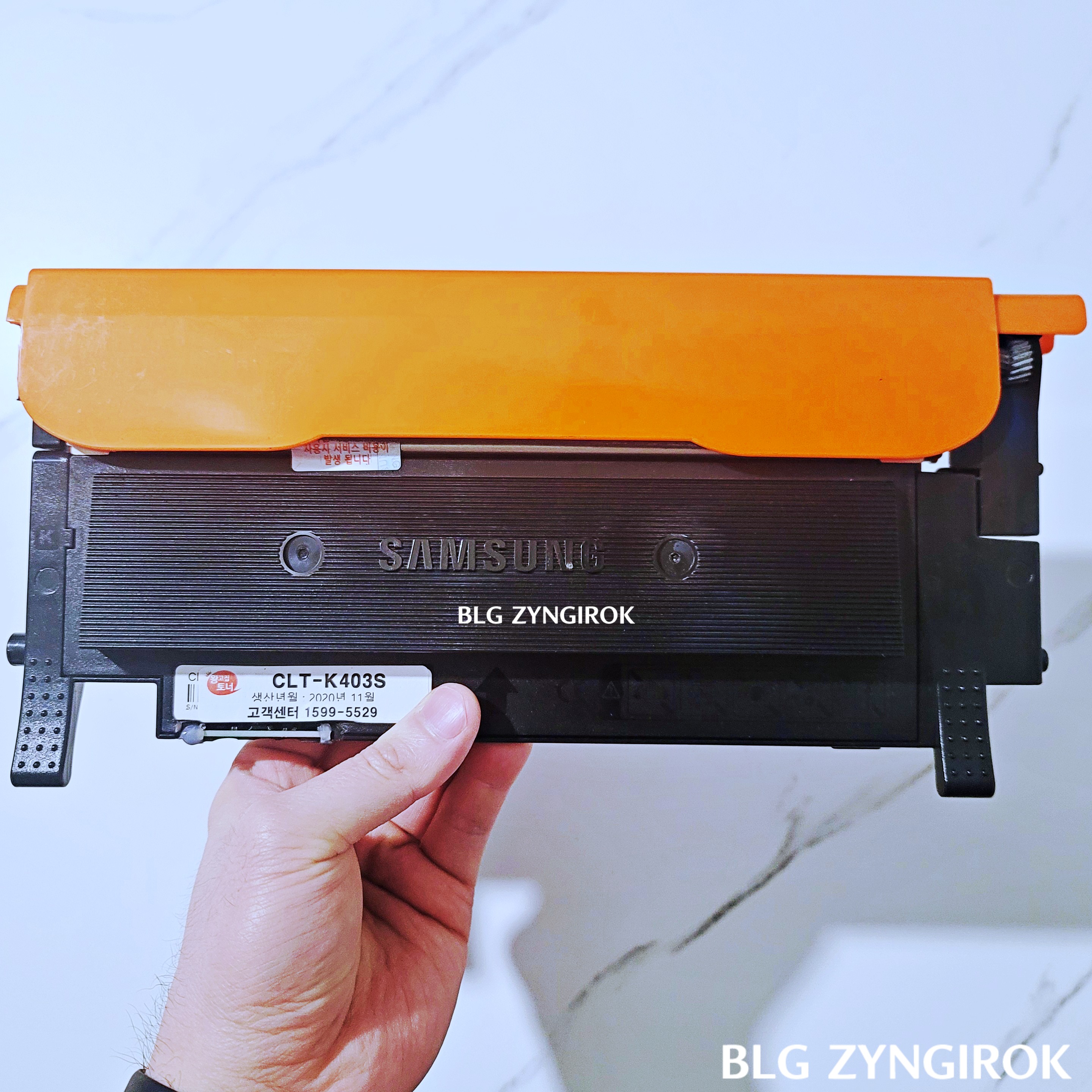 토너 캡을 부착한 토너를 들고있는 모습이다.