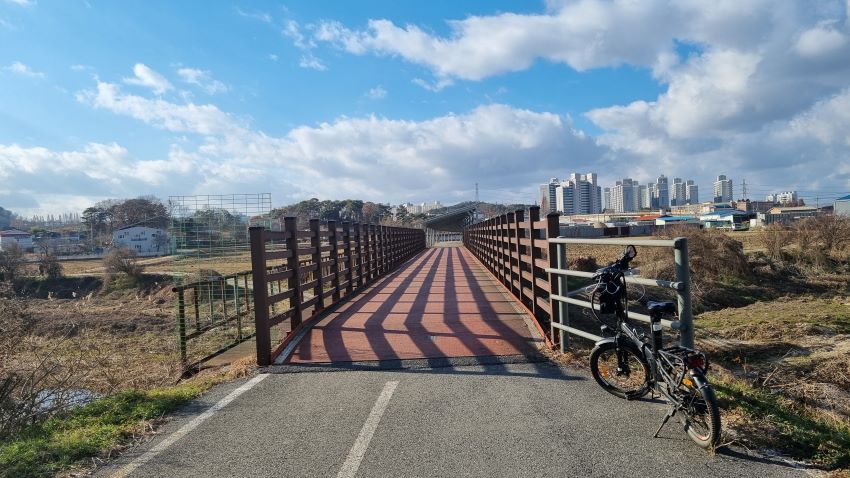 푸른하늘, 흰구름, 개울을 건너는 작은 철교, 앞에 세워 놓은 자전거, 철교의 난간 그림자,