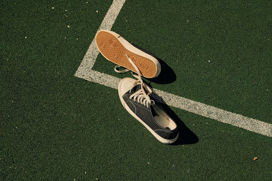 Lone sneakers on a green sports field, symbolizing stillness and solitude.