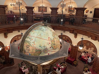 대형 지구본 공중에 떠 있고 밑에 테이블과 사람들이 있는 식당 내부 사진