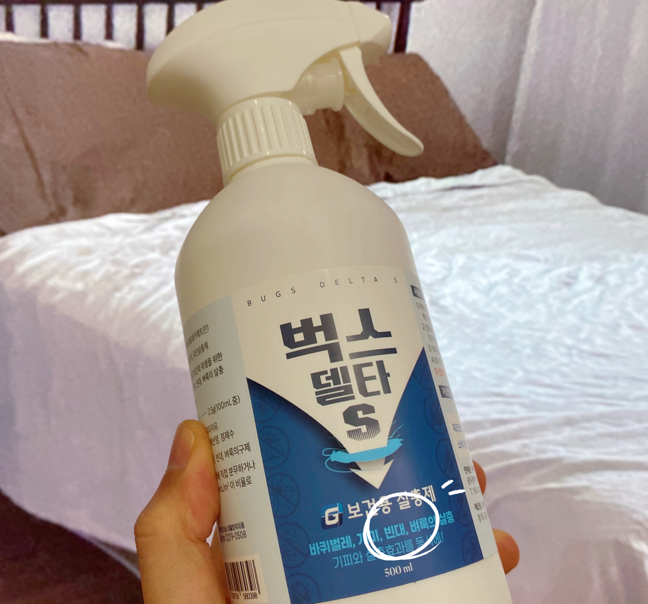 침실 배경으로 벅스델타 S 스프레이 제품을 든 손