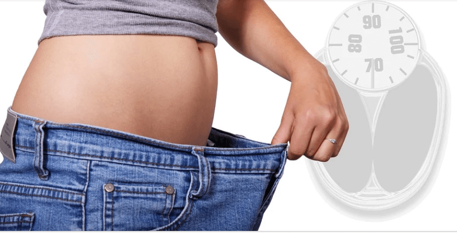 저울과 함께 다이어트 성공으로 청바지가 얼마나 크게 보이는지 청바지를 입고 확인 시켜주고 있다