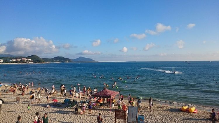 하이난 싼야 해변에서 여름을 즐기는 사람들, 맑은 하늘 아래 제트스키와 해수욕을 즐기며 활기찬 분위기를 보여주는 풍경