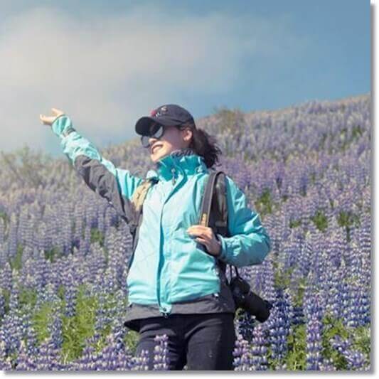 루피니 콩 꽃이 만발한 들판에서 손을 흔들고 있는 여성