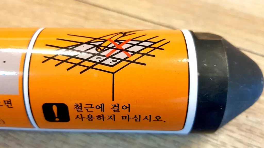 진동봉 헤드에 부착된 주의사항 중 "철근에 걸어 사용하지 마십시오" 경고 스티커.