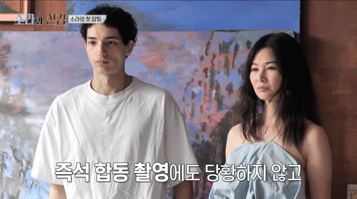 푸른빛 드레스를 입은 이소라가 흰 티셔츠의 남자 모델 옆에 선 방송 화면
