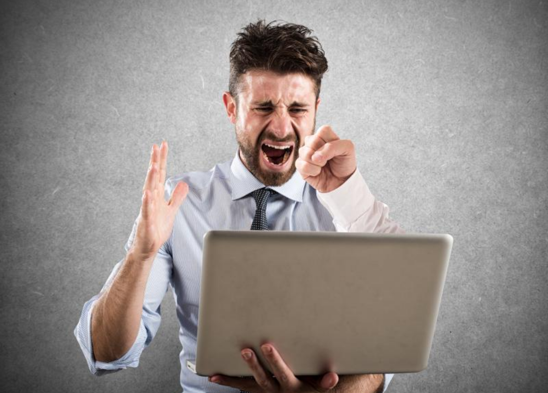 한 남자가 노트북을 들고 화를 내고 있다.