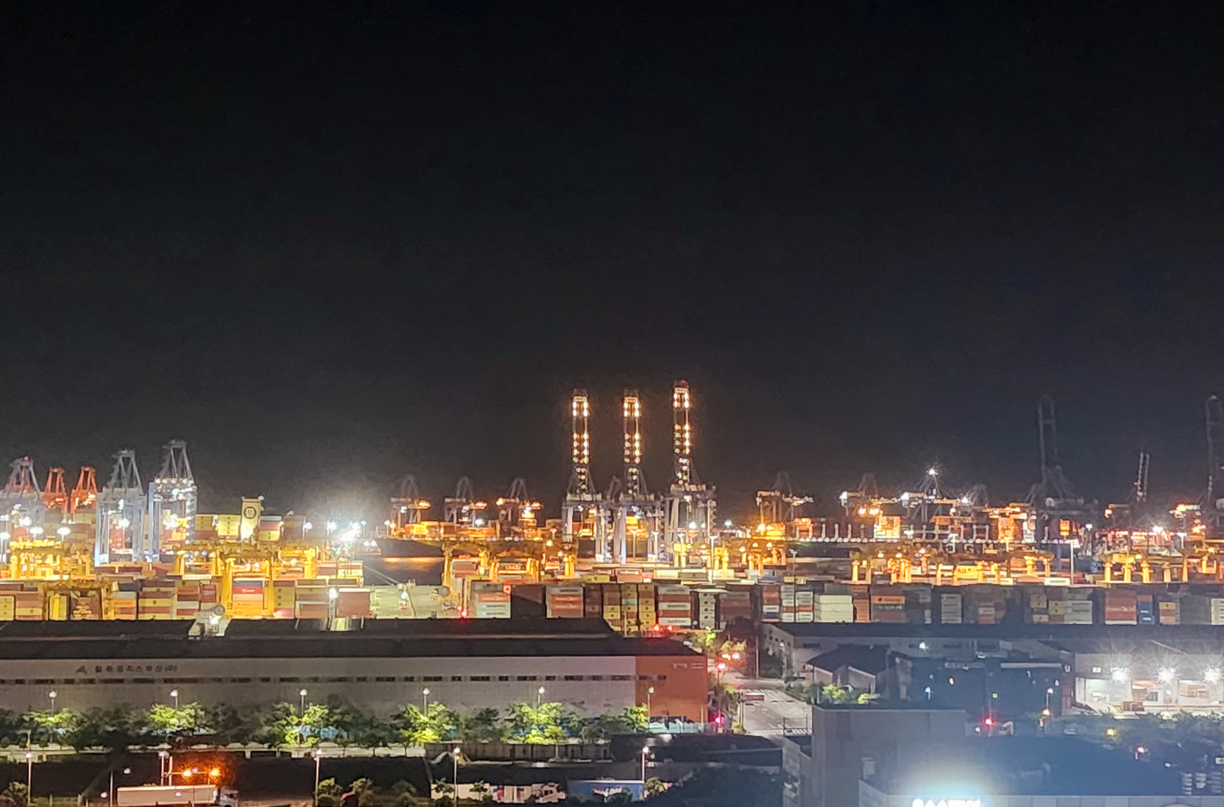 야간 조명으로 가득한 부산 신항의 컨테이너 야적장과 크레인들. 밤에도 쉼 없이 돌아가는 항만 작업 현장의 모습.