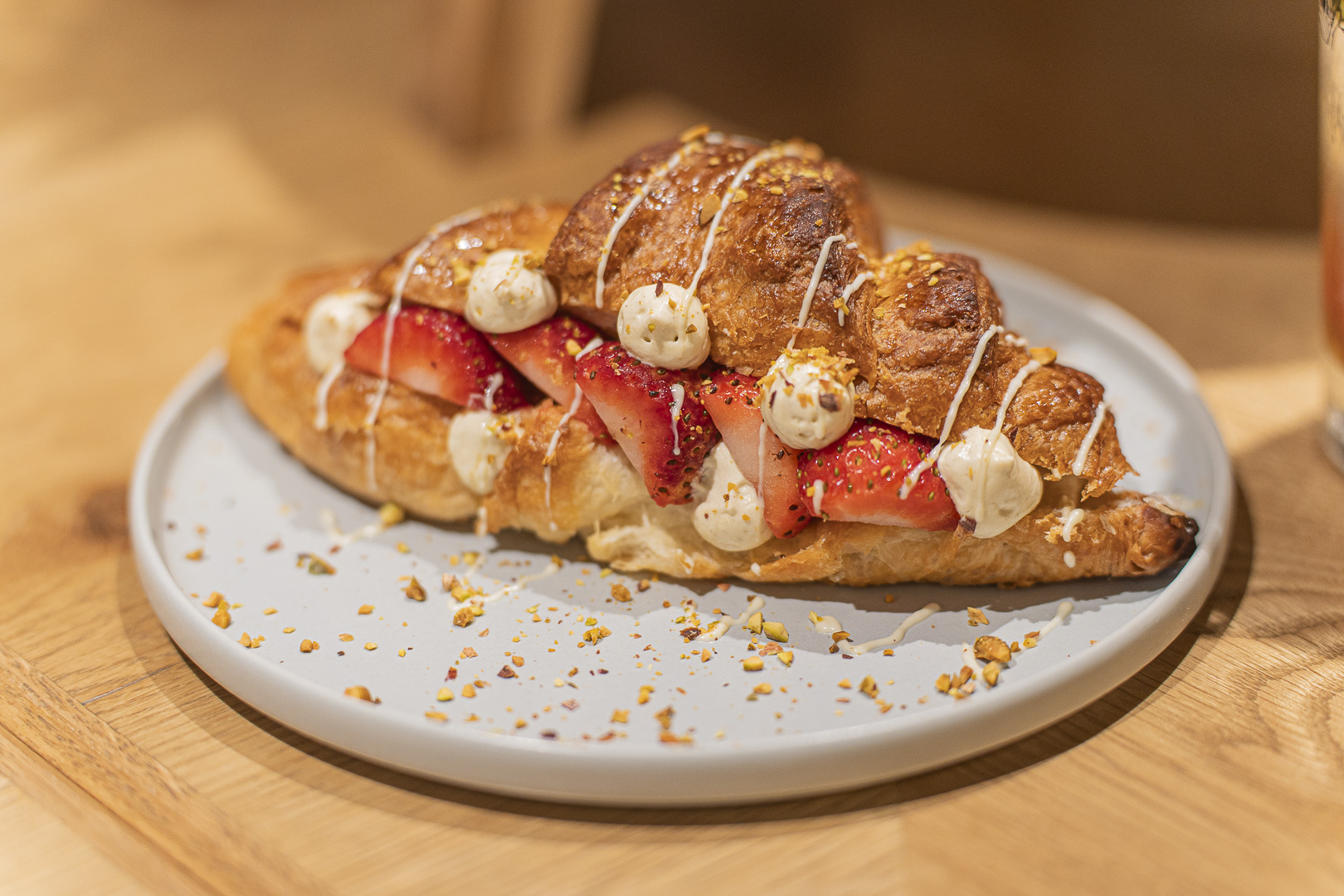 Café sinoa: a plated croissant dessert filled and decorated with strawberries and cream.