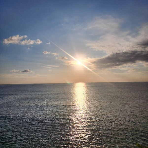 바다 위로 내려 않기 시작한 태양. 아주 맑은 하늘에 구름이 약간 있다.