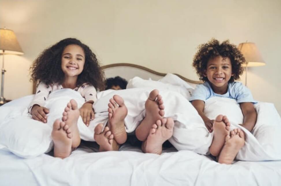 네 명의 남매가 침대 위에 누워 있다