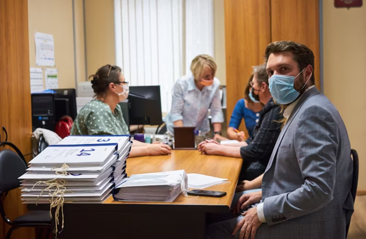 사무실 책상에 둘러앉아 상담 중인 사람들과 마스크를 쓴 직원.