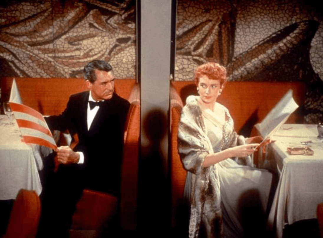 레스토랑에 앉아 메뉴판을 펼친 채 뒤에 있는 서로를 바라보는 남녀 주인공