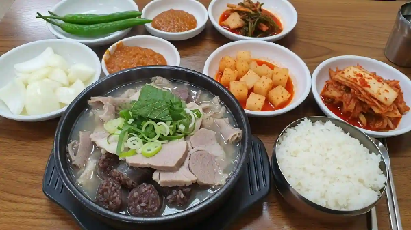 식당에서 밥, 순댓국, 깍두기, 김치, 고추, 생양파, 된장이 테이블에 올려져 있는 모습