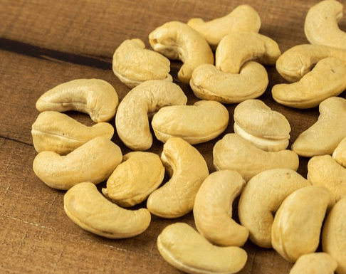 나무 바닥에 베이지색의 캐슈너트들이 수십개 갈려있다. 모양은 살짝 구부러진 긴 타원형이다.