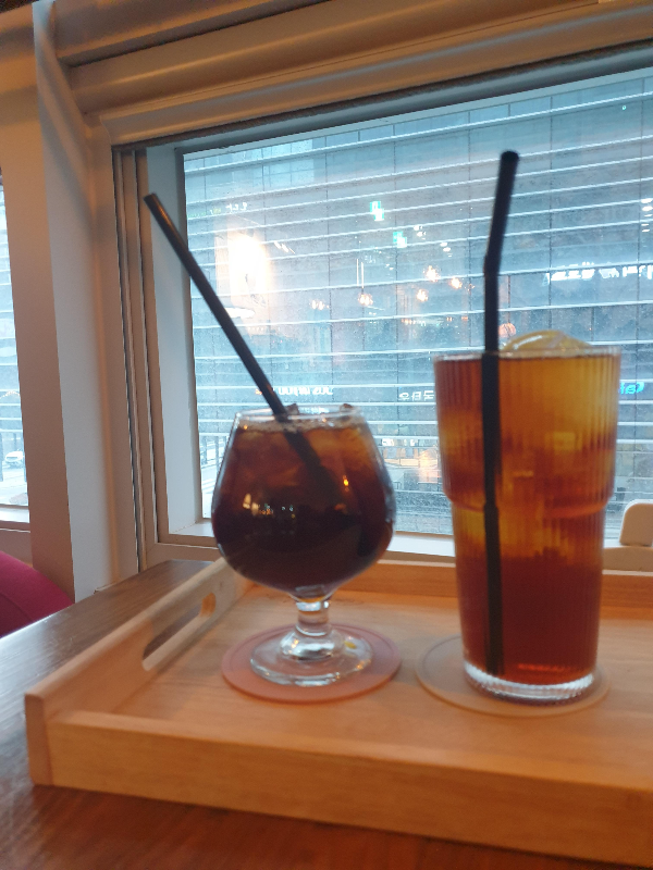 창가엔 놓인 두 잔의 커피. 하나는 브랜디잔 다른 하나는 커피 잔에 들어있다.