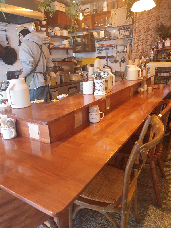 나무로 만들어진 바 테이블. 오픈형 주방에서 일하고 있는 사장님