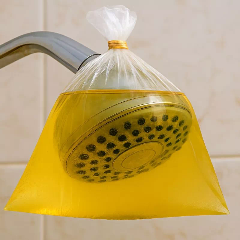 샤워기 수압 약할 때 해결을 위해 식초를 담은 비닐봉지를 샤워 헤드에 묶어놓은 모습