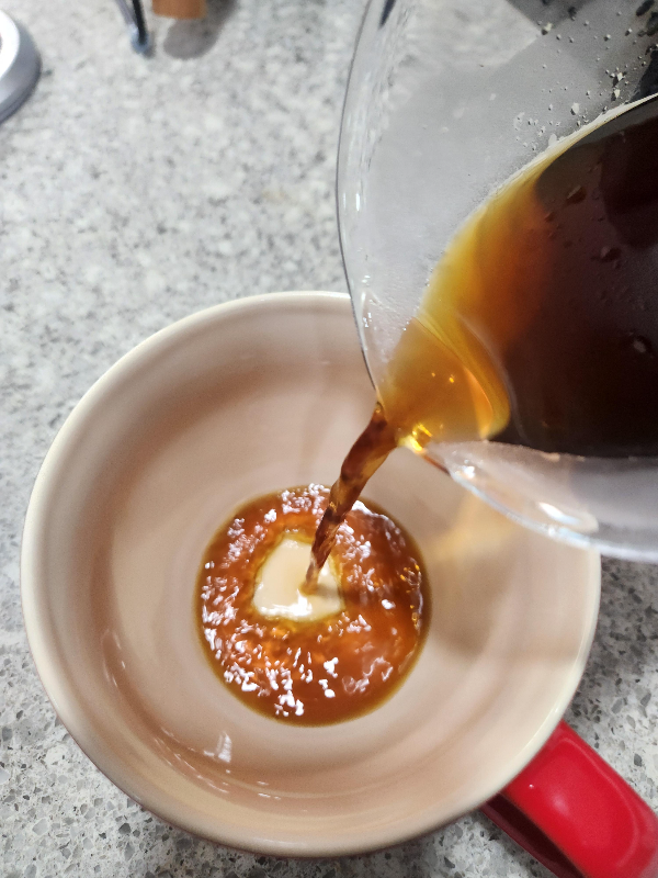 붉은 커피 잔에 추출된 커피를 따르는 모습