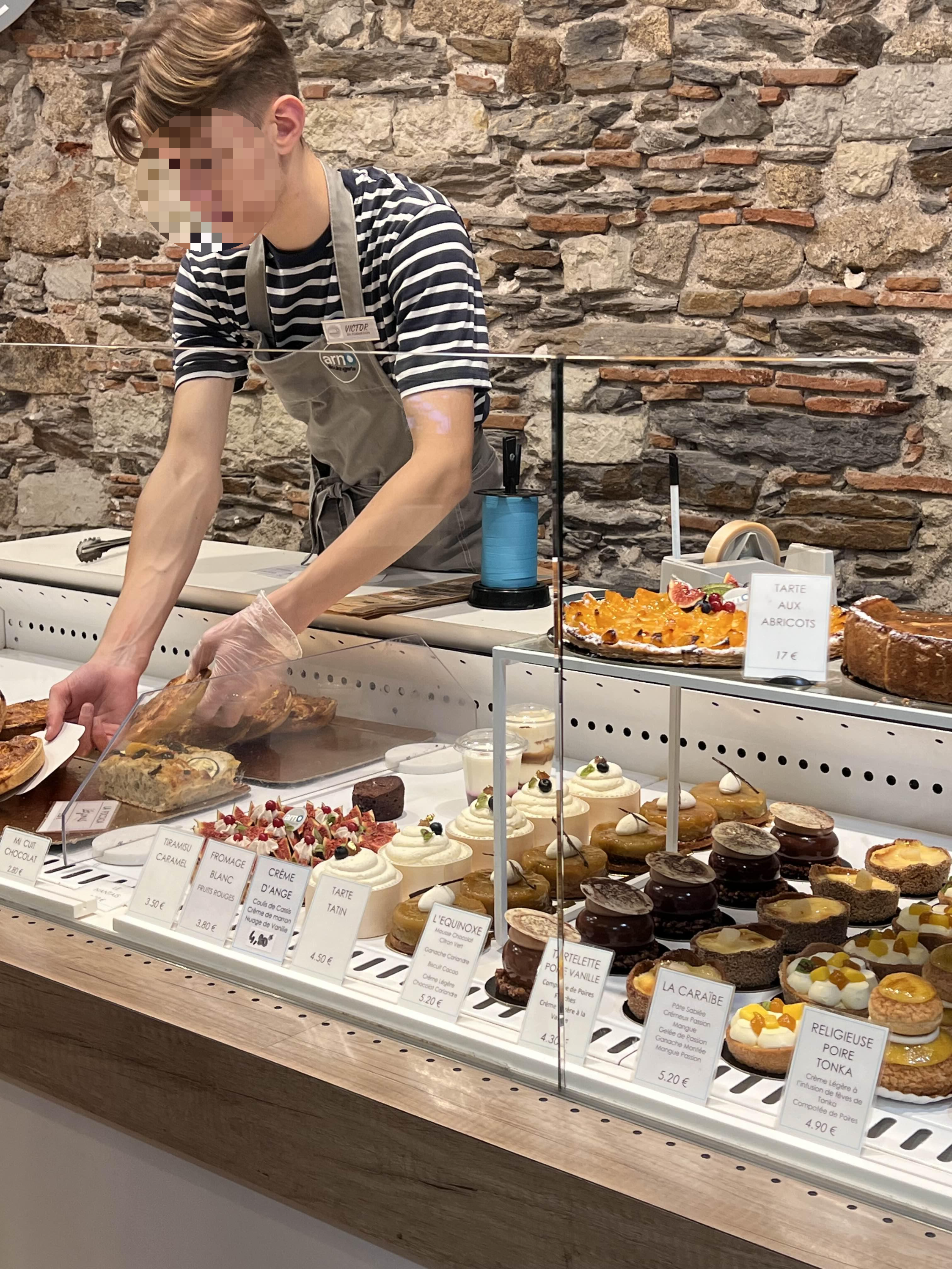빵집 직원이 타르트를 집어가고 있는 사진