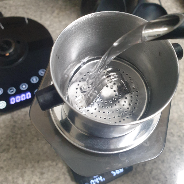 에어로프레스 위에 베트남 핀을 놓고 그 위에 물을 붓는 모습