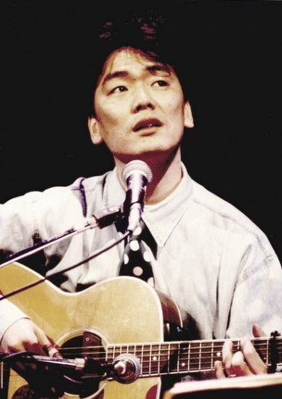 김광석-그날들-악보-김광석이-셔츠를-입고-타이를-멘-상태로-기타를-치며-허공을-응시하는-사진