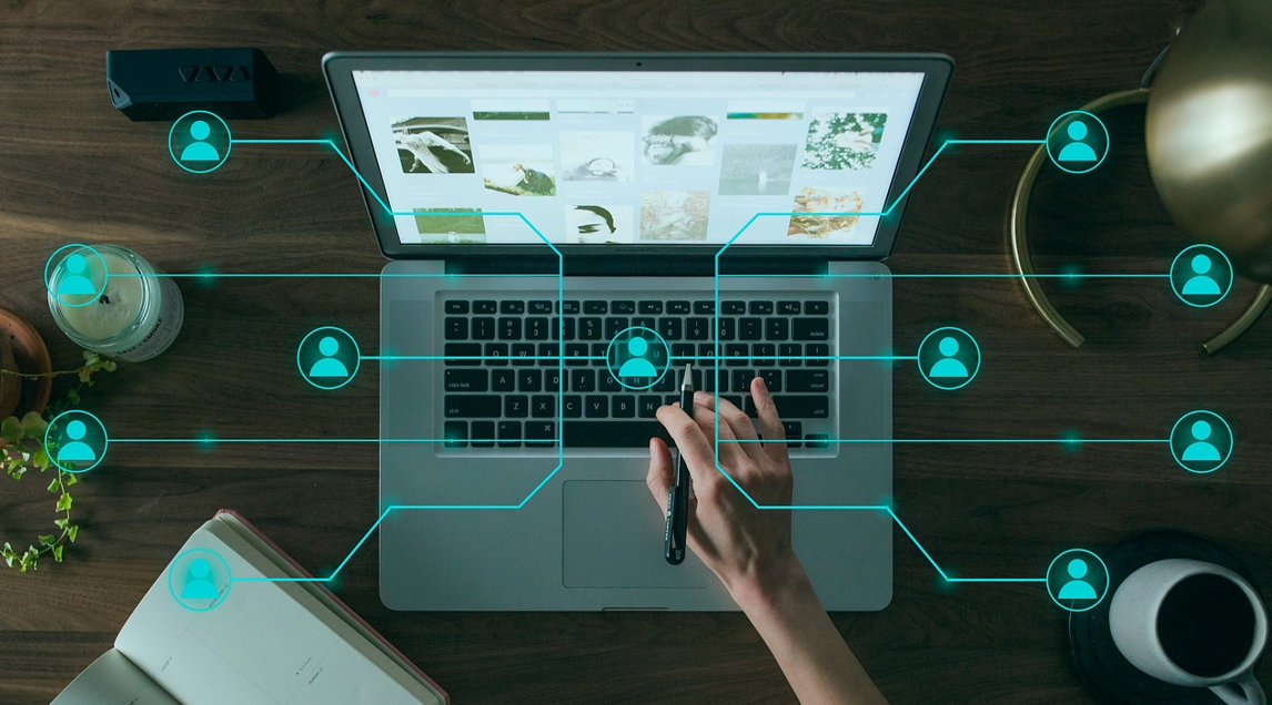 책상에 노트북이 펼쳐져 있고 이미지 위에 네트워크 연결 아이콘이 그려져 있다