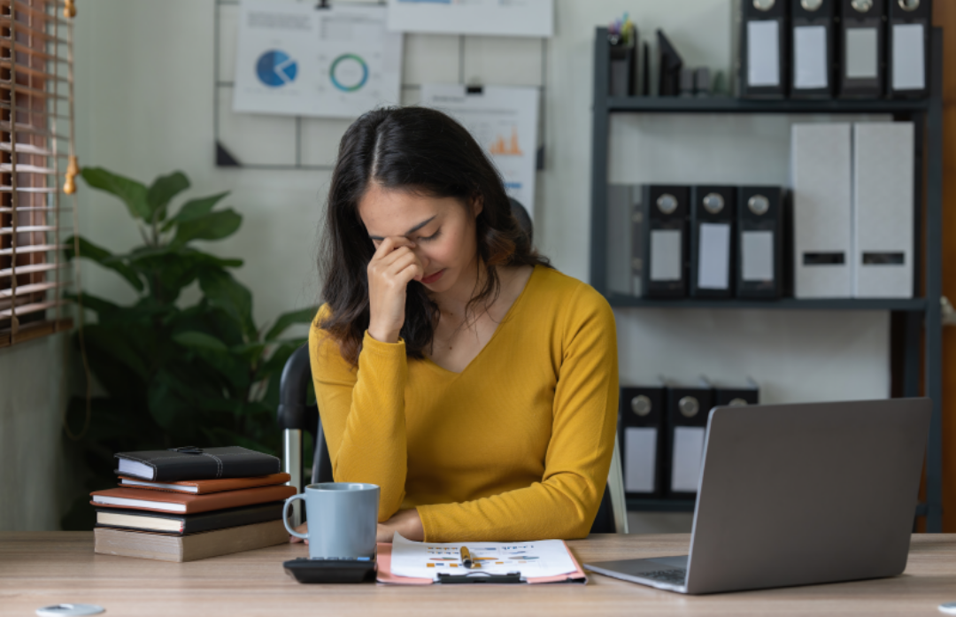 한 여성이 노트북을 하다말고 신경을 쓰며 괴로워 하고 있다.