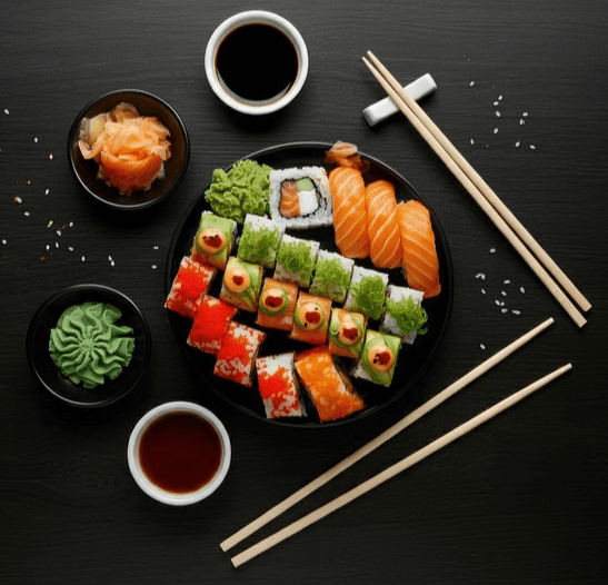 검정 식탁에 초밥이 있다. 연어초밥, 김밥이다.