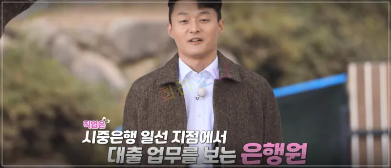 영식이 같은 장소에서 이야기하는 모습이다. 그는 갈색 코트를 입고 있으며&amp;#44; 화면에는 그의 직업 정보가 표시되어 있다. 자막: 