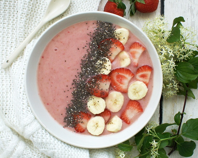 딸기 요거트 위에 딸기와 바나나로 장식되어 있고 치아씨드가 올라간 든든하고 먹음직스러운 요거트 볼