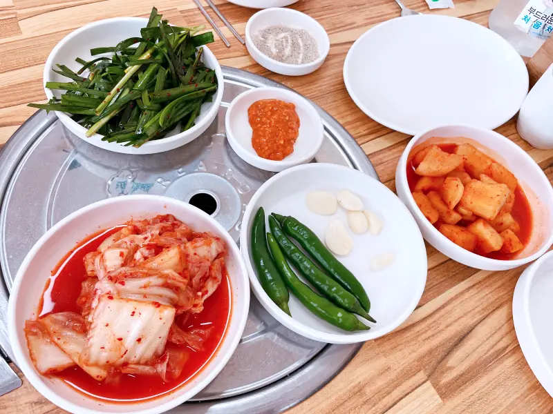 기본 밑반찬 부추, 청양고추, 마늘, 김치, 깍두기가 접시에 담긴 모습
