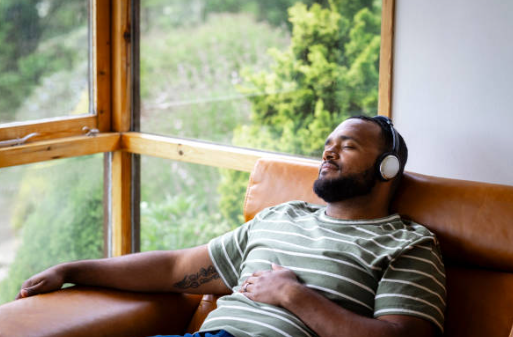 소파에서 음악을 들으면서 잠을 자는 남성 모습의 사진