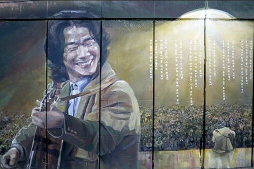 김광석-나의-노래-악보-김광석이-기타를-연주하며-활짝-웃는-모습과-무대에-앉아-관객을-마주하는-뒷모습을-그린-그림