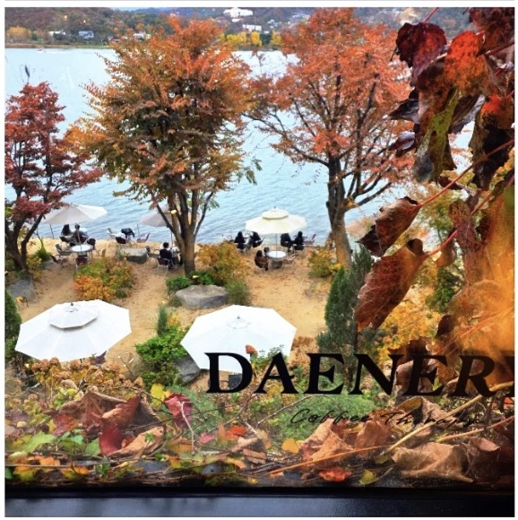 데너리스 창가에서 내려다본 북한강 정원 풍경. 파라솔 아래로 사람들이 앉아 강을 바라보고 있는 모습