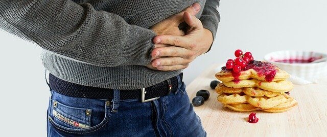 장염으로 고통 받는 남성과 테이블에 올려진 핫케이크