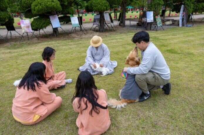 잔디밭에 강아지오 함께 앉아 홍법사 주지스님과 이야기하는 사람들