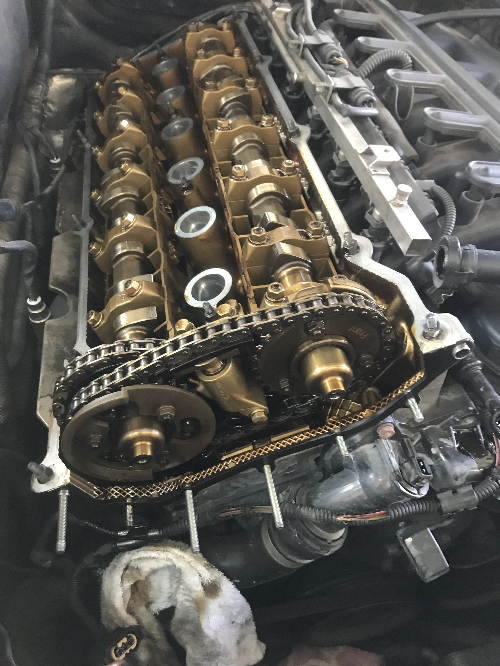 BMW 엔진 우측 시점에서 본 유압태핏 교체 전 상태, 타이밍 체인과 캠샤프트가 함께 드러난 정비 초기 단계