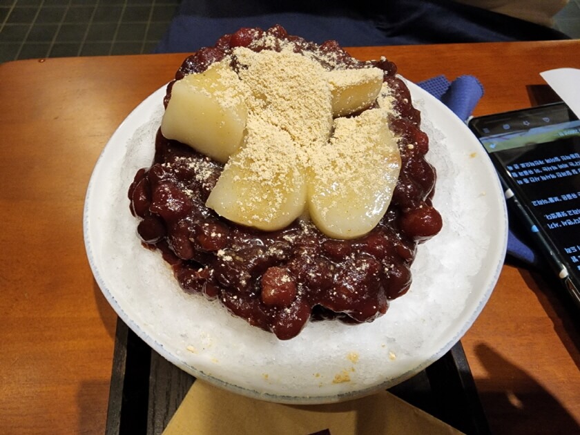 얼음 위에 팥빙수와 떡과 미숫가루가 올려져 있다.