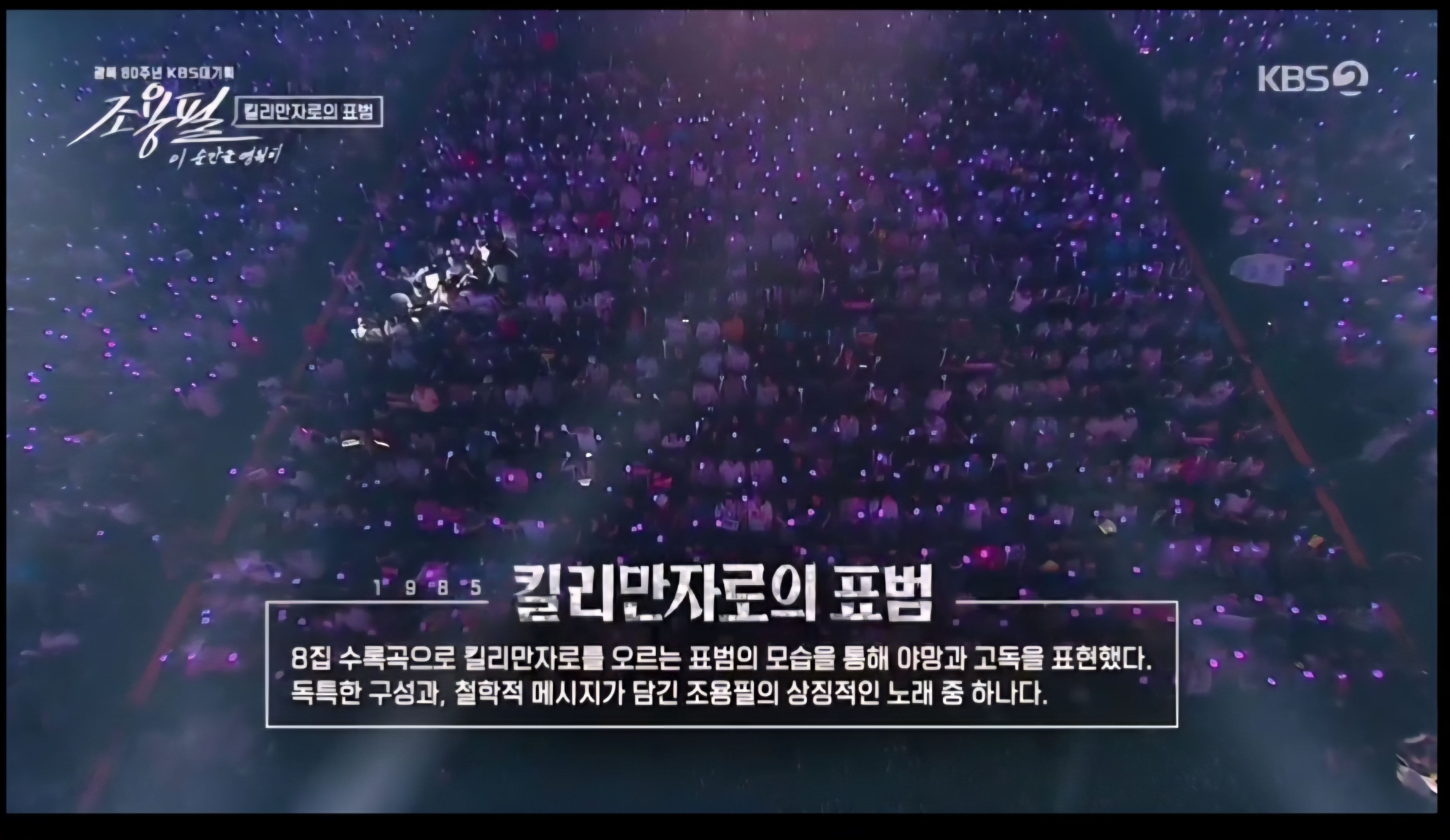 관객석 파란 조명이 빛나는 가운데, 조용필의 노래 가사가 화면에 띄워진 장면