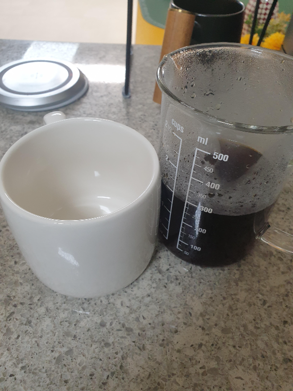 테이블 위에 컵과 커피가 든 서버가 있다.