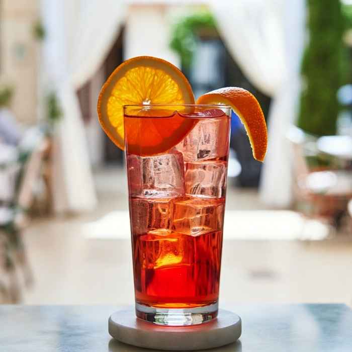 오렌지 슬라이스로 장식된 청량한 루비색의 아메리카노 칵테일 완성 사진