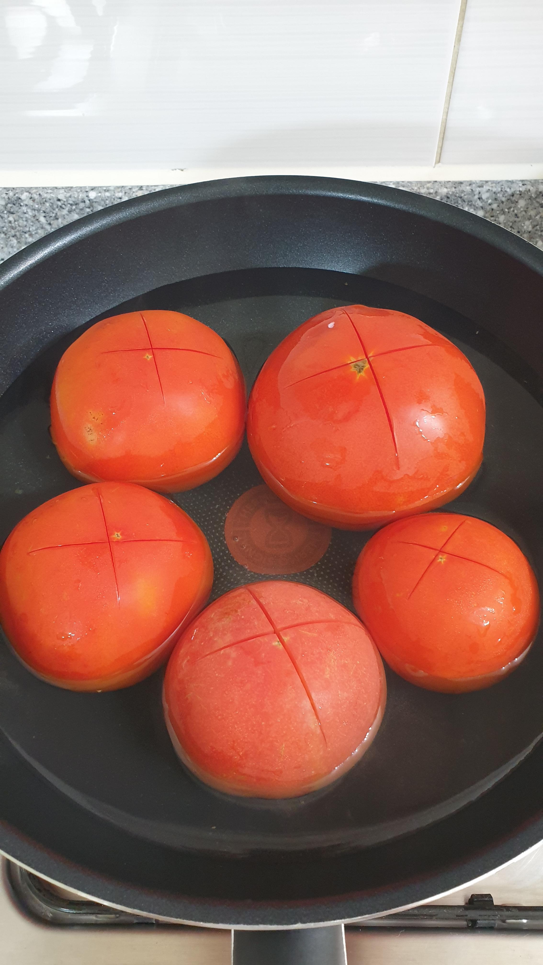 칼집을 낸 토마토를 뜨거운물에 데친다.