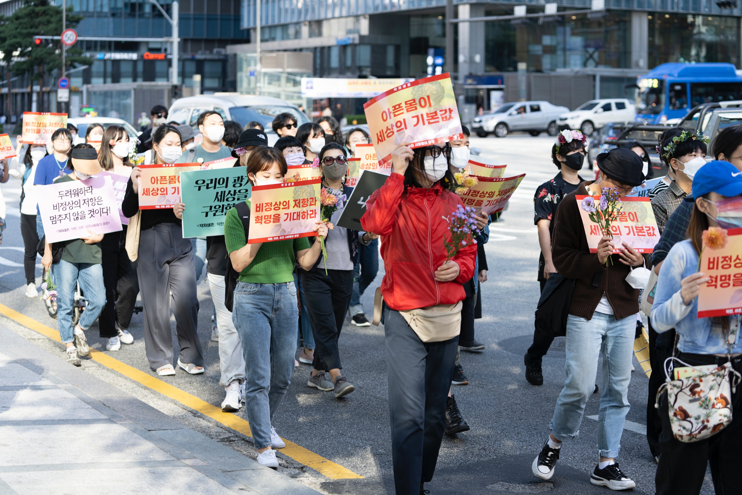 시민들이 피켓과 꽃을 들고 행진하고 있다.