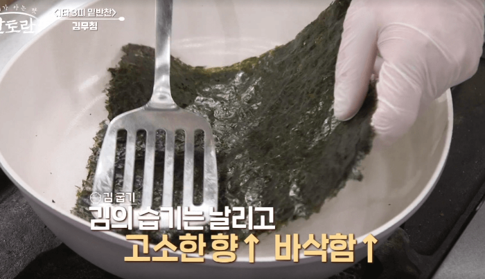 팬에 김을 뒤집개로 눌러가며 굽는 모습