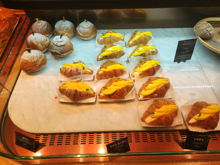 Cream buns and fruit pastries are on a plate.
